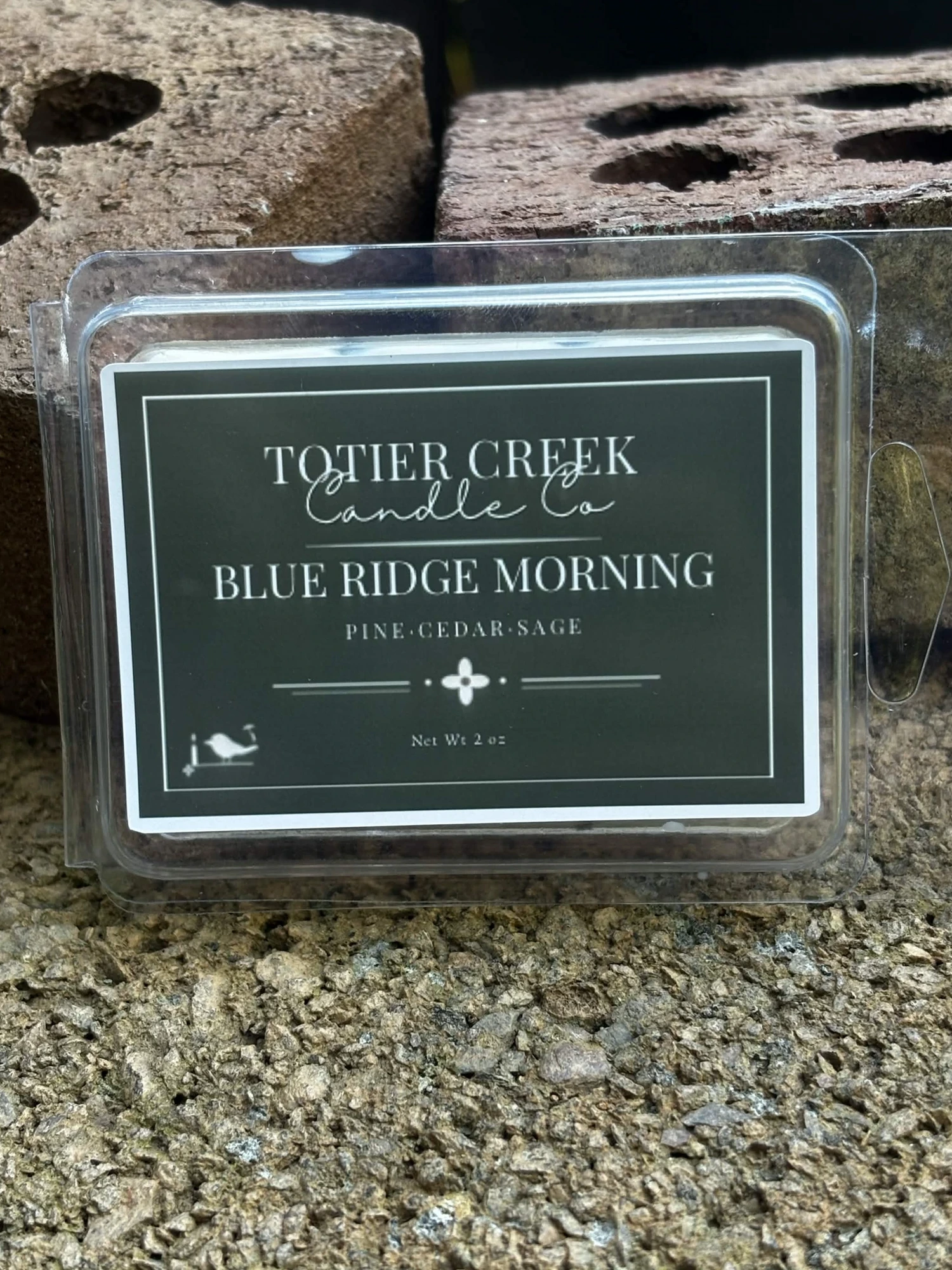 Blue Ridge Morning wax melt in a clear clamshell on creek stone