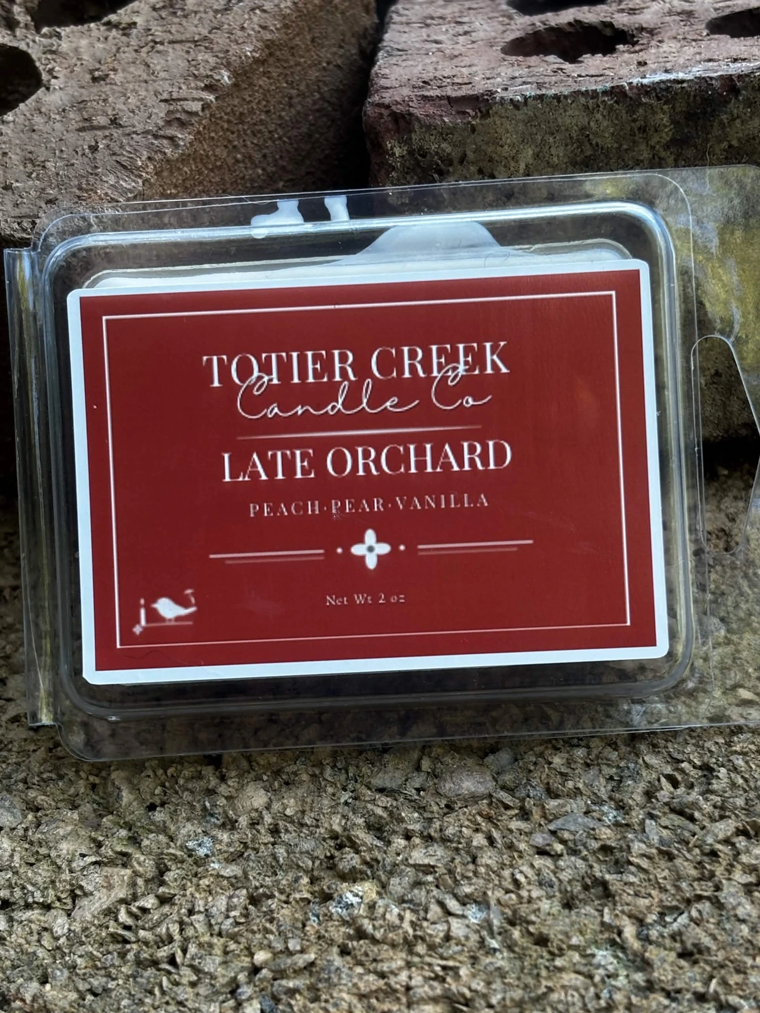 Late Orchard wax melt in a clear clamshell on creek stone
