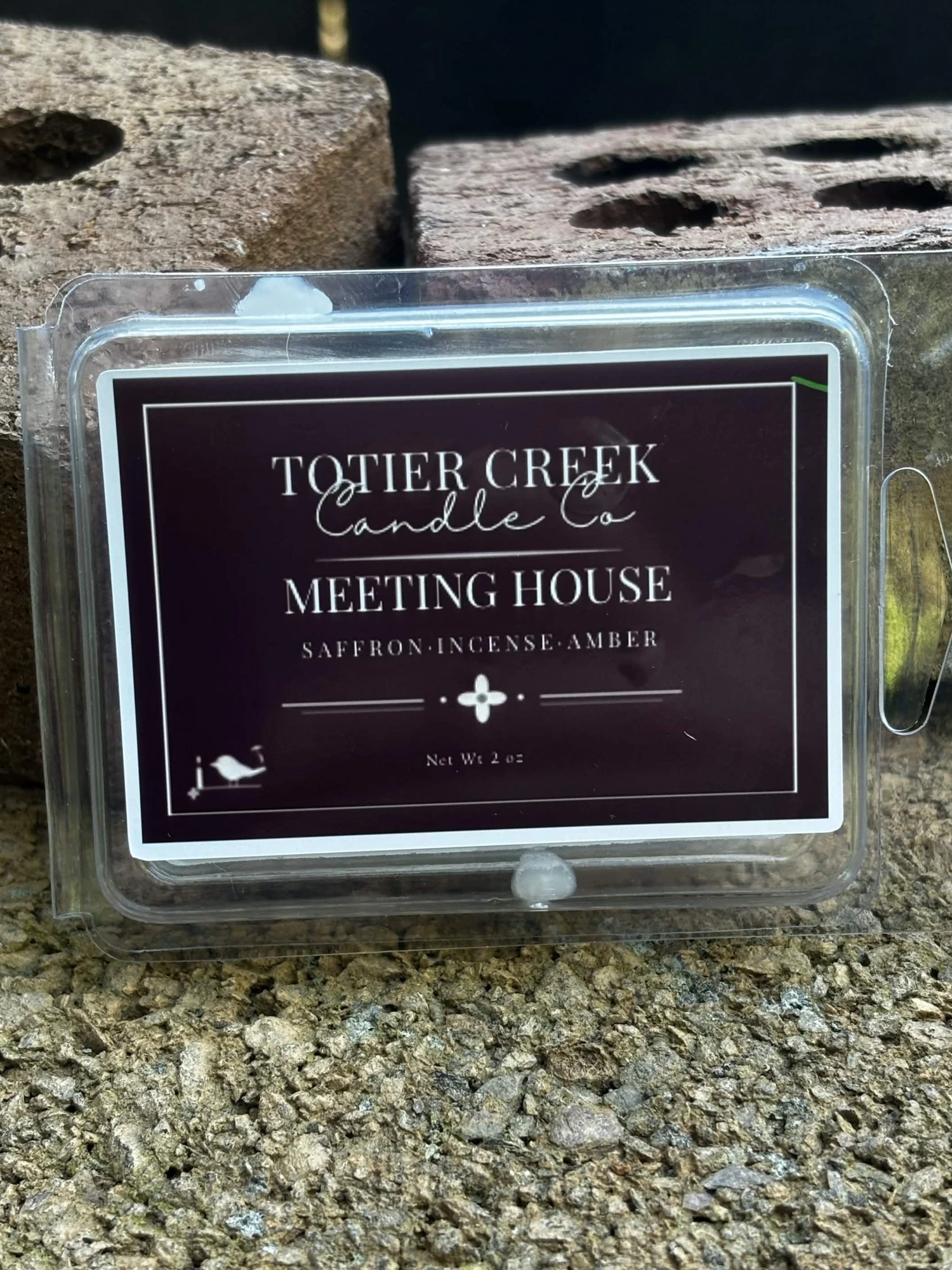 Meeting House wax melt in a clear clamshell on creek stone